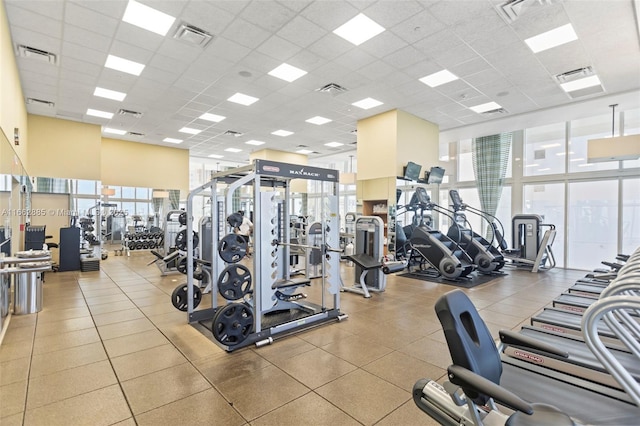 exercise room with a towering ceiling, a wealth of natural light, and a water view