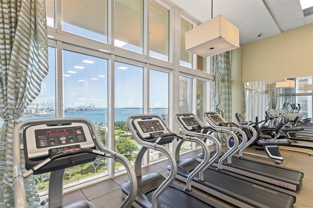 gym with a wall of windows, a water view, and visible vents