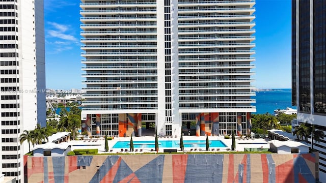 view of building exterior with a water view and a community pool