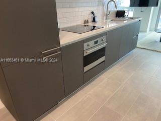 kitchen with black electric cooktop, tasteful backsplash, light tile patterned floors, and stainless steel oven