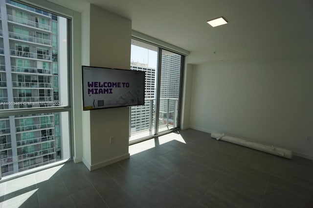 empty room with floor to ceiling windows and dark tile patterned floors