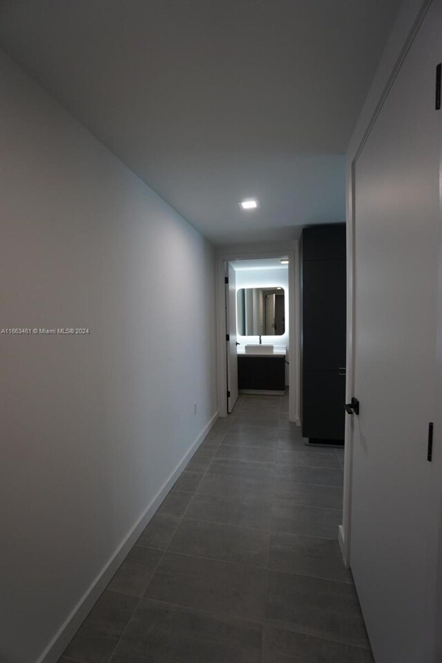 hallway featuring dark tile patterned flooring and sink