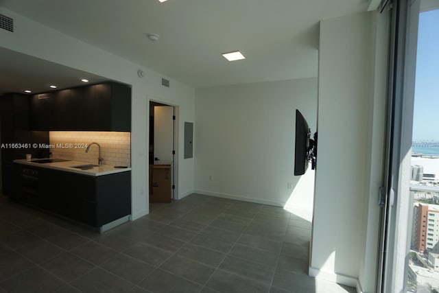 kitchen featuring backsplash, electric panel, tile patterned floors, and sink