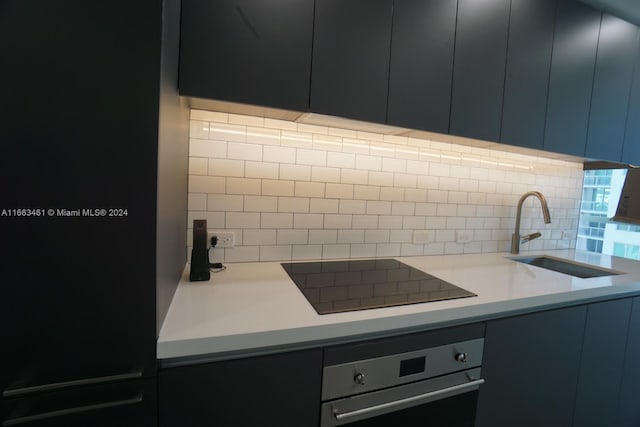 kitchen featuring black electric cooktop, sink, backsplash, and stainless steel oven