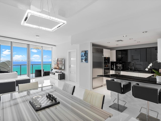 tiled dining space featuring expansive windows, a chandelier, and sink