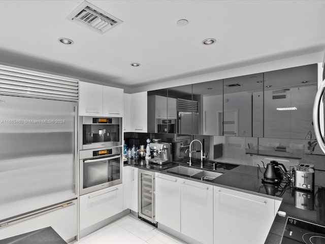 kitchen featuring white cabinetry, wine cooler, tasteful backsplash, high quality fridge, and sink