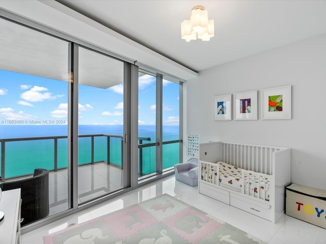 bedroom featuring a crib, a water view, tile patterned flooring, and a notable chandelier