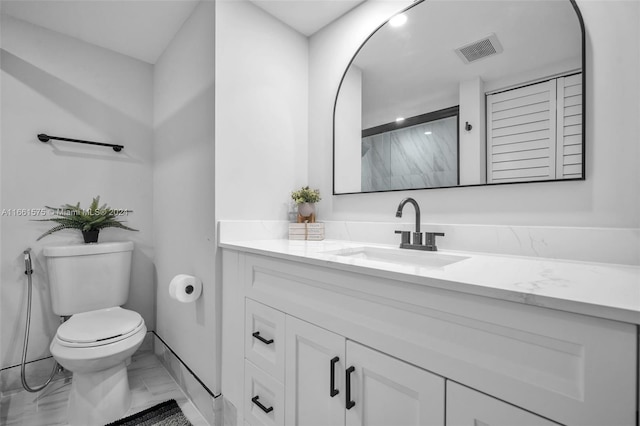 bathroom featuring vanity, a shower with shower door, and toilet