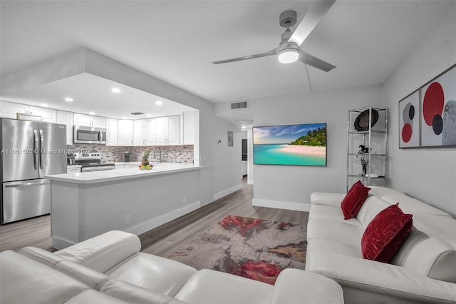 living room featuring sink, light hardwood / wood-style floors, and ceiling fan