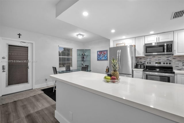 kitchen with stainless steel appliances, white cabinetry, dark hardwood / wood-style flooring, and decorative backsplash