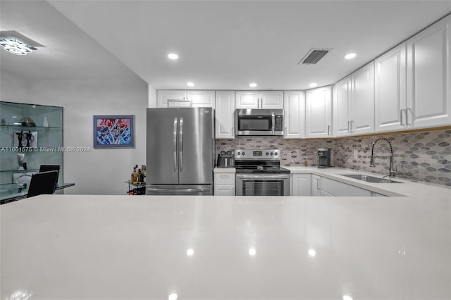 kitchen with appliances with stainless steel finishes, sink, decorative backsplash, and white cabinets