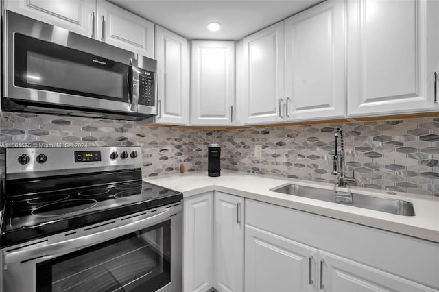 kitchen featuring sink, backsplash, white cabinets, and appliances with stainless steel finishes