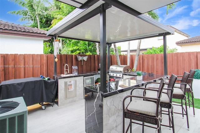 view of patio with a grill, exterior kitchen, an outdoor bar, and central AC