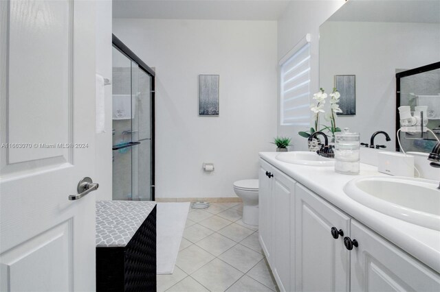 bathroom featuring tile patterned flooring, vanity, a shower with shower door, and toilet