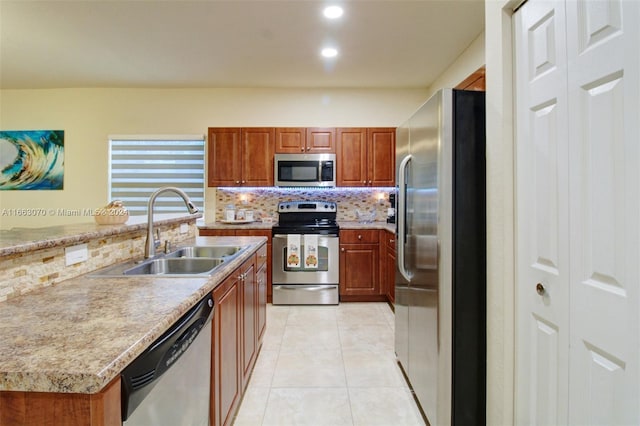 kitchen with sink, decorative backsplash, light stone countertops, light tile patterned flooring, and stainless steel appliances