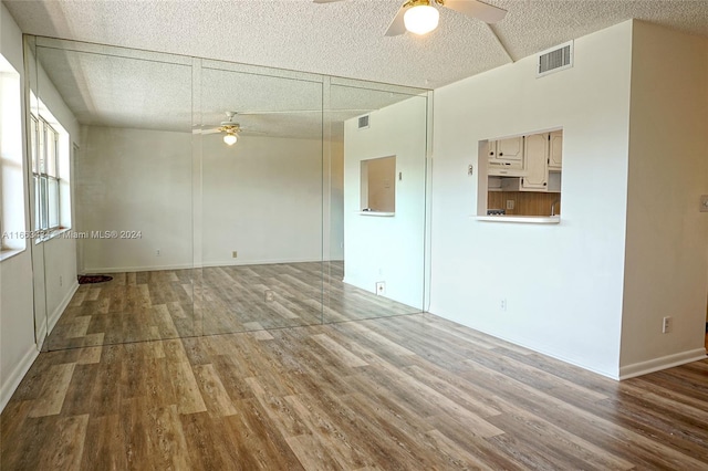 spare room featuring ceiling fan, wood-type flooring, and a textured ceiling