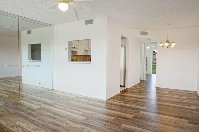 empty room featuring dark hardwood / wood-style flooring, ceiling fan with notable chandelier, and a textured ceiling