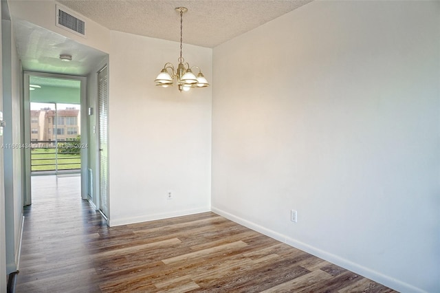 unfurnished room featuring a notable chandelier, wood-type flooring, and a textured ceiling