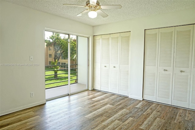 unfurnished bedroom with access to exterior, a textured ceiling, two closets, ceiling fan, and light hardwood / wood-style flooring