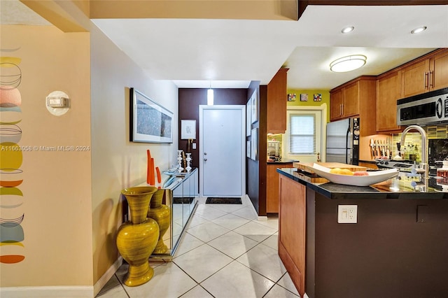 kitchen with light tile patterned floors, stainless steel appliances, and kitchen peninsula