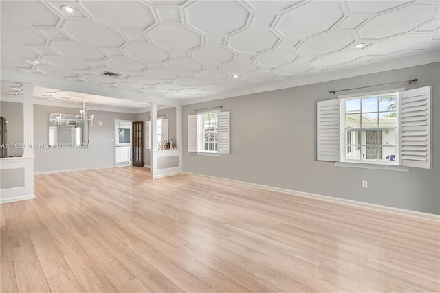 unfurnished living room featuring light wood-type flooring, ornate columns, a wealth of natural light, and crown molding