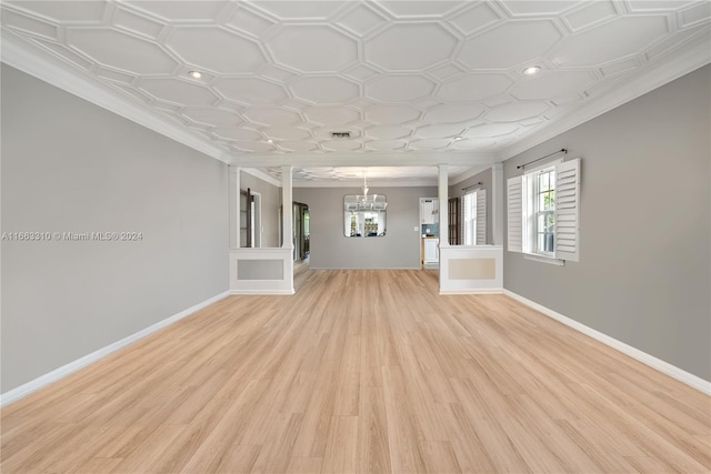 unfurnished living room with baseboards, light wood-type flooring, a notable chandelier, and crown molding