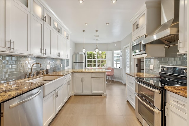 kitchen with white cabinets, wall chimney exhaust hood, appliances with stainless steel finishes, and decorative backsplash