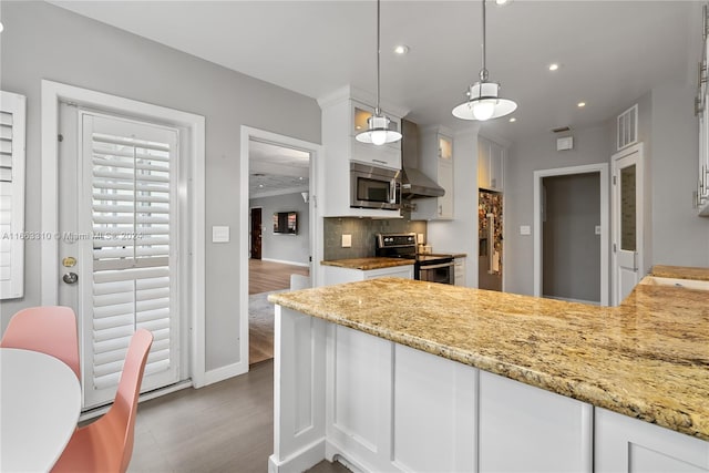kitchen featuring recessed lighting, appliances with stainless steel finishes, wall chimney range hood, backsplash, and white cabinetry