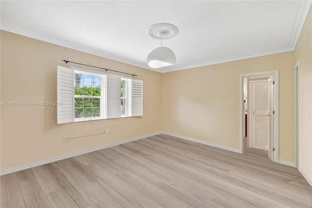 spare room featuring crown molding, light wood finished floors, and baseboards