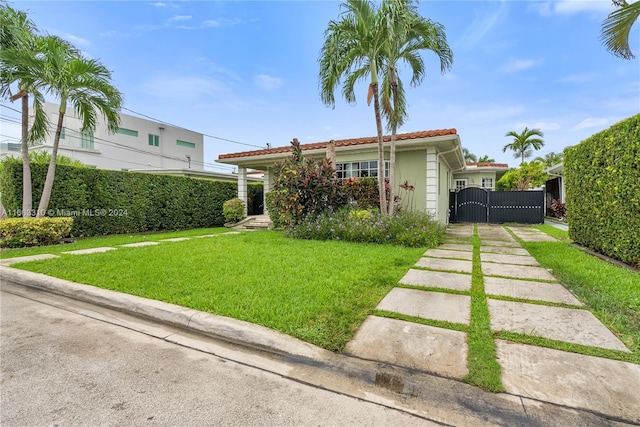view of front facade with a front yard, a gate, a tiled roof, stucco siding, and fence