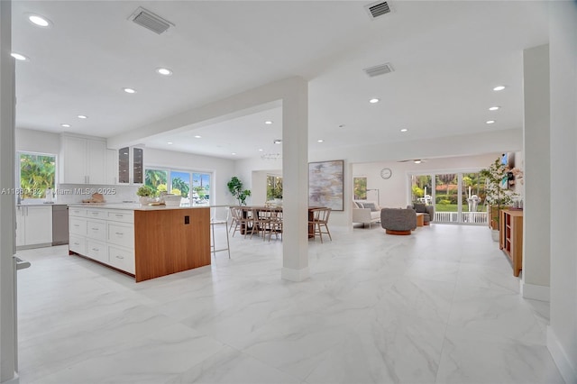 kitchen with a kitchen bar, a wealth of natural light, a center island, and white cabinets