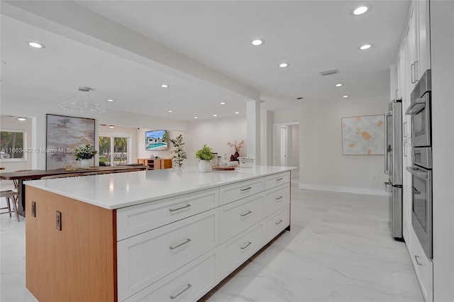 kitchen with high end fridge, a spacious island, white cabinetry, and hanging light fixtures