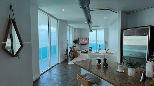 kitchen with dark stone countertops, built in refrigerator, and floor to ceiling windows