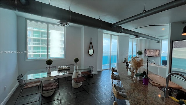 tiled dining space featuring sink and a water view