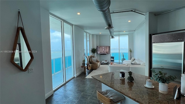 kitchen with dark stone countertops, stainless steel built in fridge, and white cabinets