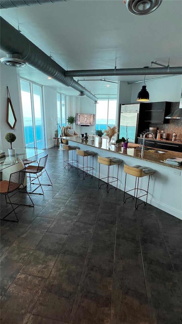 kitchen featuring dark tile patterned flooring, sink, a kitchen bar, high end refrigerator, and decorative backsplash