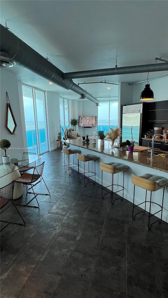 kitchen with a wealth of natural light, sink, a water view, and a breakfast bar