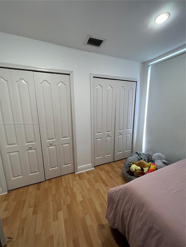 bedroom with light hardwood / wood-style flooring and two closets