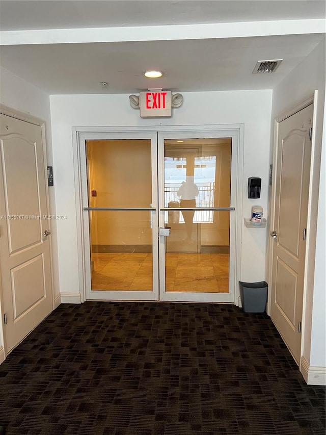 corridor featuring dark colored carpet and french doors