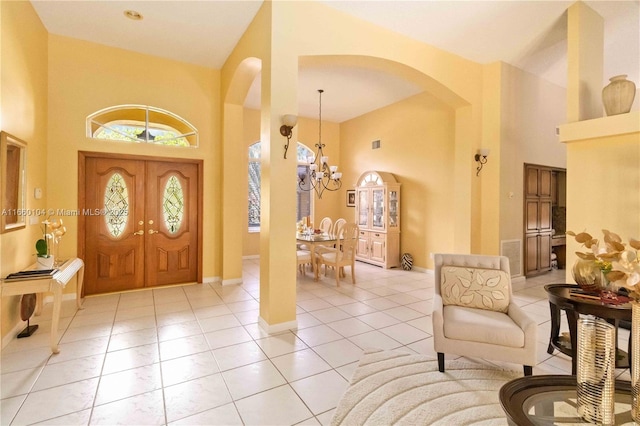 entrance foyer featuring an inviting chandelier, light tile patterned floors, and a high ceiling