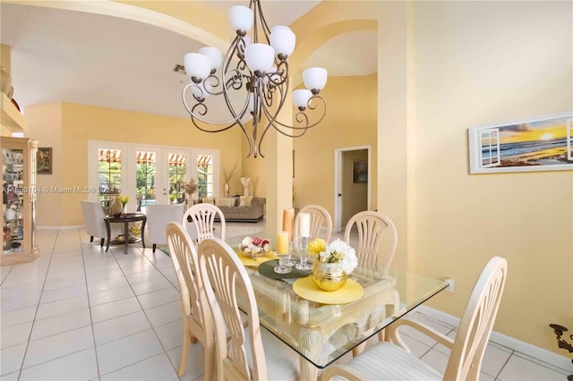 tiled dining room with a high ceiling, a chandelier, and french doors