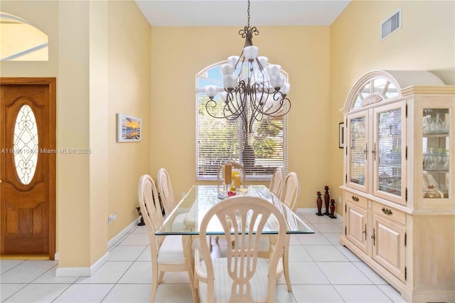 tiled dining room with a towering ceiling and a chandelier