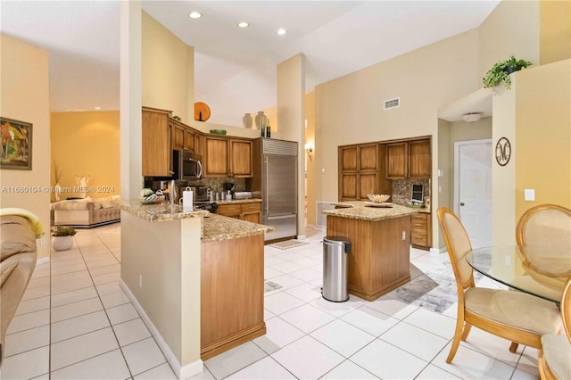 kitchen featuring stainless steel appliances, backsplash, kitchen peninsula, and a kitchen island