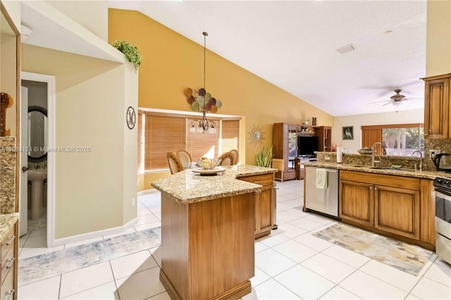 kitchen with appliances with stainless steel finishes, hanging light fixtures, a center island, light tile patterned floors, and light stone counters