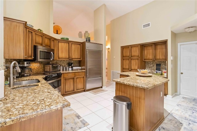 kitchen with light stone counters, sink, light tile patterned floors, and stainless steel appliances