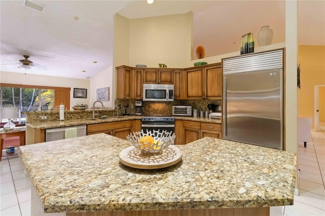 kitchen featuring a kitchen island, appliances with stainless steel finishes, sink, backsplash, and kitchen peninsula