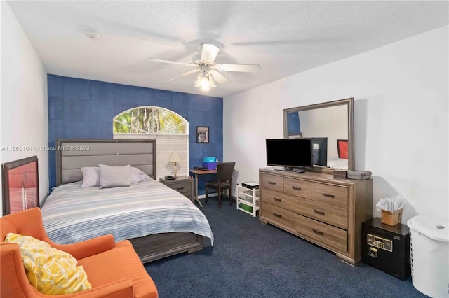 bedroom featuring a textured ceiling, dark carpet, and ceiling fan