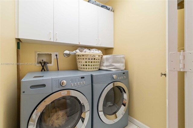 clothes washing area with washer and clothes dryer and cabinets