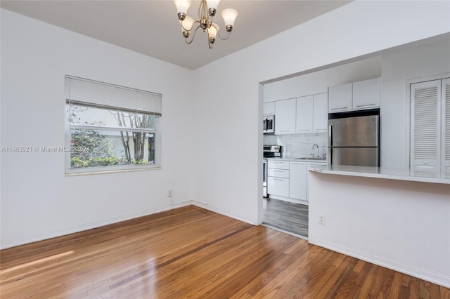 unfurnished living room featuring sink, a chandelier, and hardwood / wood-style floors