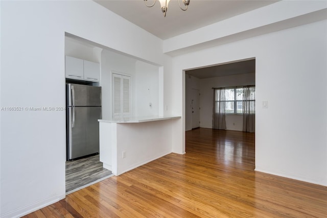 spare room with an inviting chandelier and light wood-type flooring